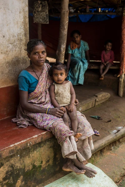 On Kamala's lap is Aardini, her grand daughter. In the background, her daughter Rekha and son Karthik. 
Rekha lives in Ulippu, Hospatta, at her husband's house. 
Rekha has an elder brother. The photograph is taken from Gerthila Area, Kadaba, in Karnataka.