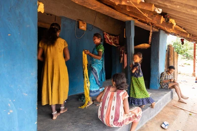 Wife (blue saree) preparing to go to the police station as her husband was caught while transporting marijuana from their village to town. On her left and right, their daughters. Those who sitting on the veranda are neighbours. Chitangaru village, Bordering with Andra Pradesh. Chitrakonda, Malkangiri district/2023 