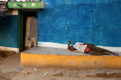 A drunkard is having a nap on the Varanda and a cow is peeping out from the house. Take from a village in the periphery of Raipur. 